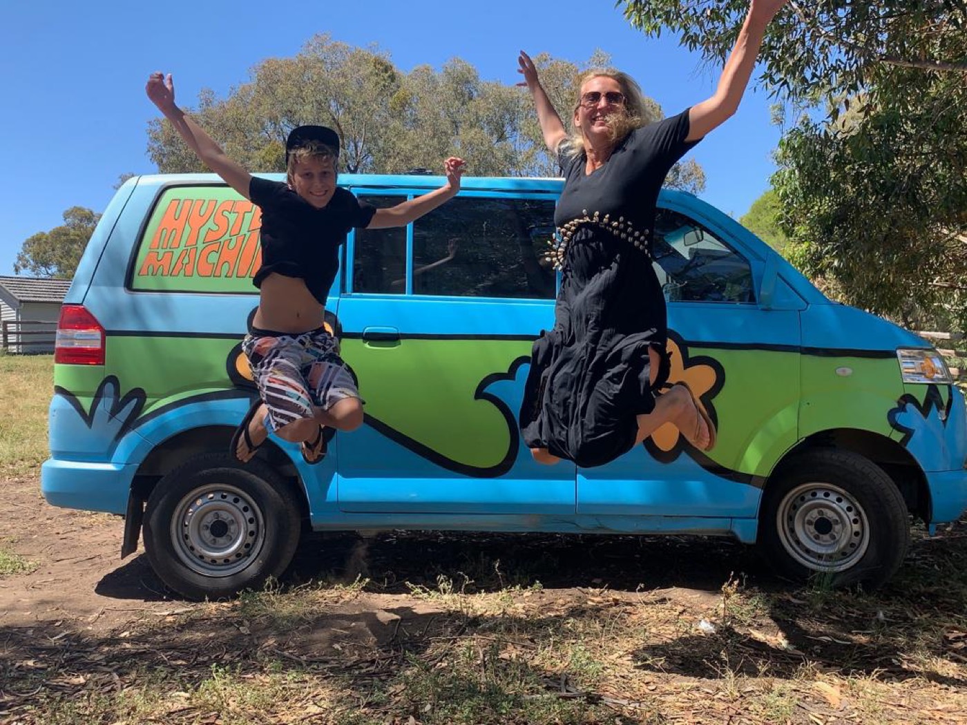 Maria und Timo springen vor einem bunten Campervan in Australien in die Luft